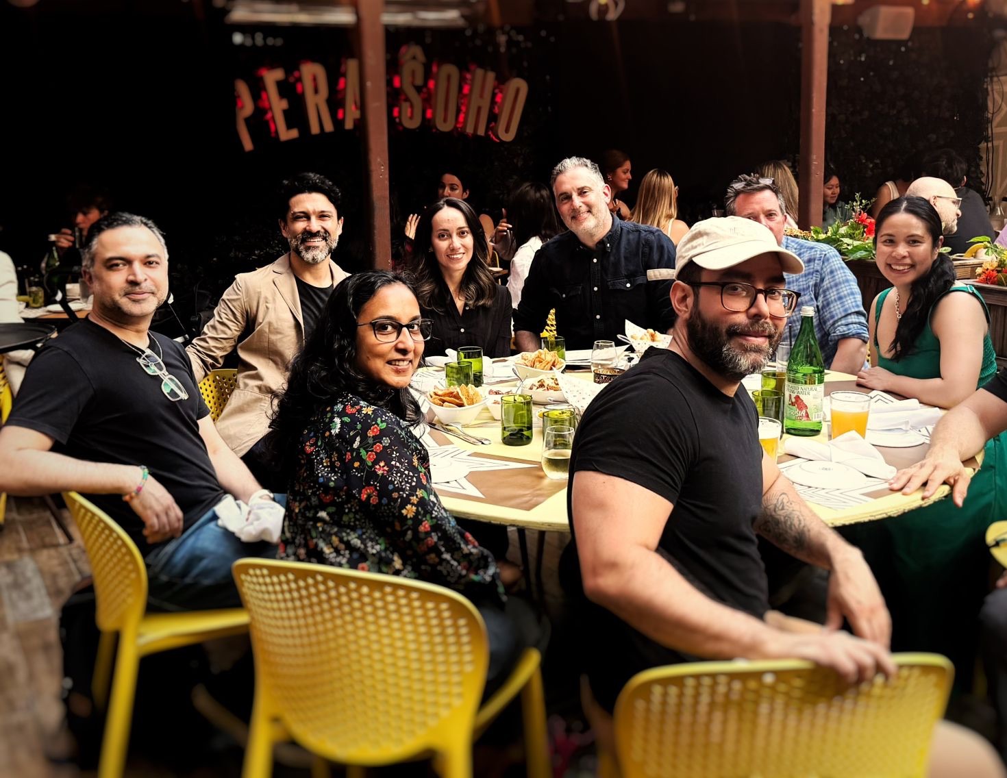 TAP NYC attendees around a dinner table on a restaurant patio, smiling at the camera
